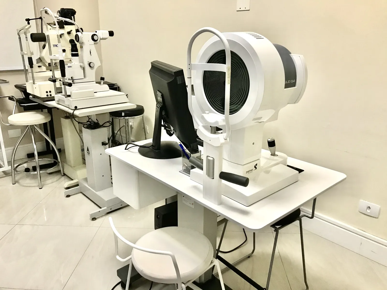 Lâmpada de fenda e equipamentos de exame sobre a mesa branca da sala de exames